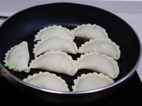 平底锅烧热，倒入适量的适量花生油，均匀码入韭菜盒子、中小火煎至外皮焦黄。