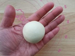 左手按住馅料球，右手往上推，收口收紧，收口朝下放置。