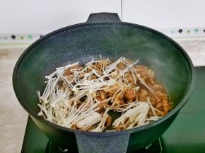 起油锅倒入腌制好的肉丝翻炒至变色，加入金针菇。