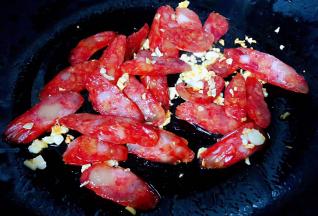 锅中倒入底油加热放入蒜粒爆香再放入腊肠炒香