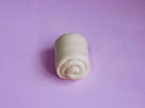 取一块面团再次擀长舌状，由下往上卷起来，收口处捏紧。