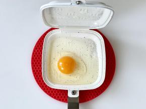 把三明治烤盘预热好后，盘里刷一层油，磕入一个鸡蛋，然后扣好烤盘。