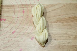 顶端捏紧，分开的两条馅料朝上，编辫子一样扭成麻花状，底部捏紧。整理成长条。