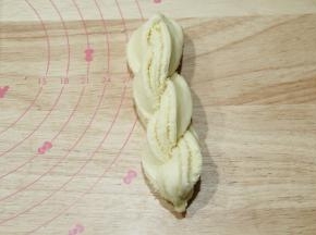 顶端捏紧，分开的两条馅料朝上，编辫子一样扭成麻花状，底部捏紧。整理成长条。