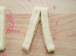 小心的略微擀宽。然后横向切成7条。取一条，从中间切开，顶端不切断。