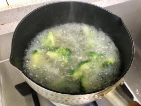 把西兰花洗净，把底部的粗茎去掉，切成小块，下沸水焯1分钟后捞出。