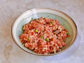 肉糜放入器具中，加入盐，十三香，1勺料酒，蚝油，酱油，葱花顺时针搅拌均匀。