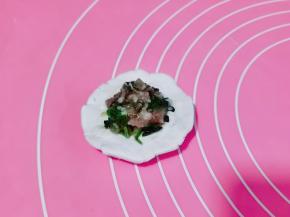 取一块面团压扁，加入肉馅包起来，收口捏紧揉圆。