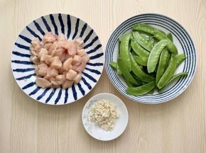 鸡胸肉洗净切成丁，把荷兰豆洗净，摘去头尾和老筋，大蒜拍碎切成末。