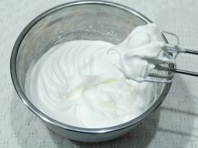 继续打到细密小泡，加入1/3糖；打到蛋白略带纹路，加入最后的糖。打到提起打蛋头呈现大弯钩（湿性发泡），转低速再打几圈，整理大气泡。