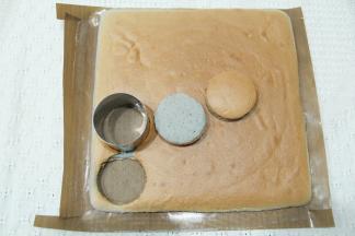 蛋糕胚烤完后取出，振出热气后，转移到冷凉架上冷凉，盖上油纸防止表皮被吹干。微温后可以倒扣，撕掉底部的油布！毛巾卷！冷凉好的蛋糕胚用圆形模具扣出蛋糕片。可以组装8个小贝。