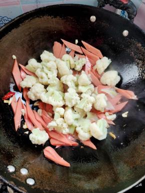 放入焯水的花菜翻炒均匀！