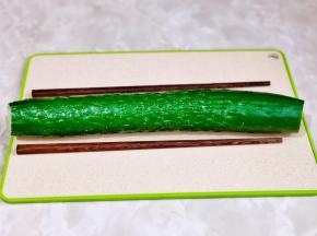 黄瓜洗净去跟去尖，放砧板上，两边各垫一根筷子。