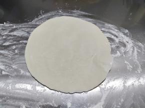 案板上撒一点面粉，然后铺一张手抓饼。手抓饼不需要解冻，软了就不好操作。