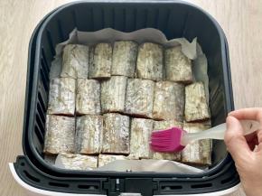 空气炸锅的炸篮里铺好硅油纸，刷一层油防粘，把腌制好的带鱼用厨房纸吸干水分，平铺在硅油纸上，然后在表面刷一层油。