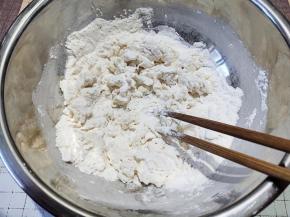 一边倒水一边用筷子将面粉搅成面絮。