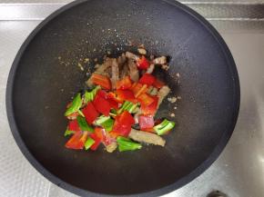 牛肉基本变色后，加入青红椒块一起翻炒至断生。