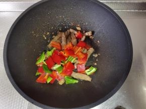 牛肉基本变色后，加入青红椒块一起翻炒至断生。