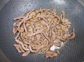 炒锅内倒适量的食用油烧热，下入腌好的牛肉翻炒至变色，盛出备用。