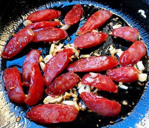 锅中倒入底油加热放入蒜粒爆香再放入腊肠炒香味