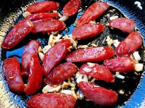 锅中倒入底油加热放入蒜粒爆香再放入腊肠炒香味
