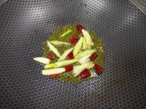 炒锅内倒适量的食用油烧热，下入葱段和干红辣椒炒香。