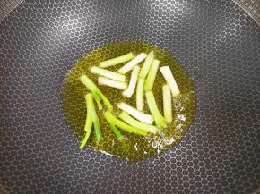 炒锅内倒适量的食用油，下入葱段。