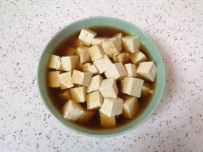 将豆腐放入大碗里，放半勺盐和2勺酱油，加入纯净水浸泡，这样可以去除豆腐的豆腥味，也可以让豆腐入一点底味。