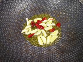 大蒜切成片，干红辣椒掰成小段，锅里继续倒油烧热，下入蒜片和干红辣椒炒香。