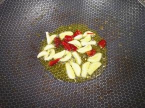 大蒜切成片，干红辣椒掰成小段，锅里继续倒油烧热，下入蒜片和干红辣椒炒香。