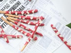 10、冷凉好的百奇棒放入草莓巧克力中，裹一薄层巧克力，再撒上杏仁脆片，完工！