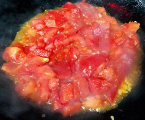 锅中倒入底油加热放入蒜粒爆香再放西红柿大火快速翻炒