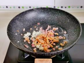 起油锅加入蒜末炒香，再加入虾米，培根丁煸炒。