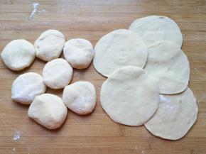 将小剂子压扁，擀成中间稍厚边缘薄的包子皮。 