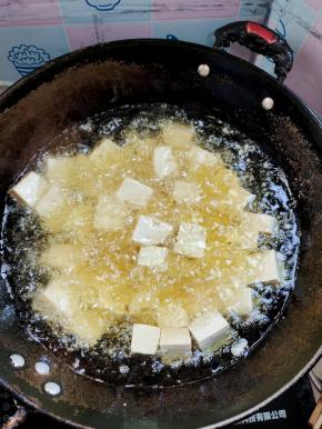 起锅烧油，油温七成热（拿一支木筷子插在油中，筷子周围冒泡泡就说明油温可以了！），放入切好的豆腐，用漏勺稍微推动一下，进行炸制！