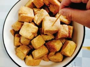 炸好的豆腐泡放入碗中，用牙签把豆腐泡扎几个小孔，方便入味儿！