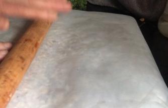 盖上油纸，用擀面杖擀压平实