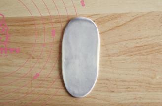 右手虎口位置往上收口收紧。全部操作完。取一收口朝上，从中间用擀面杖往上下擀开成牛舌状