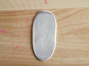 右手虎口位置往上收口收紧。全部操作完。取一收口朝上，从中间用擀面杖往上下擀开成牛舌状