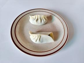 取一张饺子皮，四周抹一点水，放上肉馅，饺子皮中间先捏在一起，然后包起来即可。