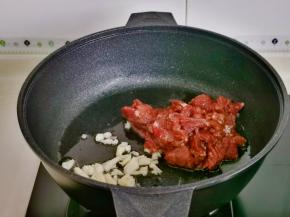 起油锅，加入蒜末煸炒，再加入腌制好的牛肉。