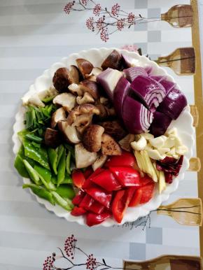 准备好所需的配菜：
青椒和红椒去蒂洗净切成块，泡发好的香菇切成小块，洋葱切成块，蒜瓣切成小块，生姜切成丝，干辣椒切成段备用！