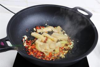 炒锅烧热，倒入适量花生油，放大蒜、生姜、干辣椒、红辣椒，小火煸炒香。接着放入酸笋，继续煸炒至酸笋的香味。