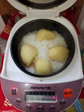 米淘洗干净，加入1.5倍的水，上面放一个削皮洗净的大土豆，盖上盖子，按煮饭键！（今天买的土豆有点大，我把它改刀切成四半，这样土豆更容易蒸熟！）