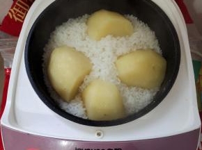 米淘洗干净，加入1.5倍的水，上面放一个削皮洗净的大土豆，盖上盖子，按煮饭键！（今天买的土豆有点大，我把它改刀切成四半，这样土豆更容易蒸熟！）