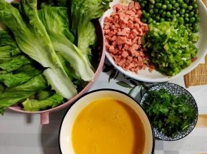 青豆焯水捞出沥干水分，火腿肠切成小丁，螺丝椒去蒂切成小丁，香菜切成段。生菜洗净，土鸡蛋打散备用！