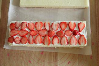 取一蛋糕片，抹上一层淡奶油，放上草莓片，再抹一薄层奶油，用抹刀抹平。