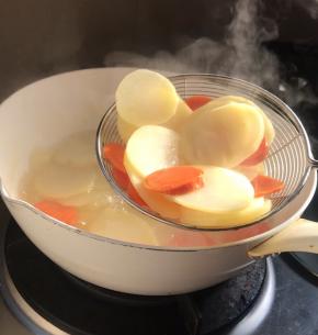 锅中烧开水，加盐放入土豆和红萝卜煮断生，捞出备用