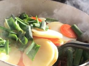 倒入土豆片和青蒜叶翻炒均匀