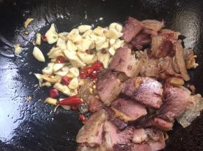 把腊肉扒到一边，放入花椒，生姜，蒜瓣，干辣椒爆香！